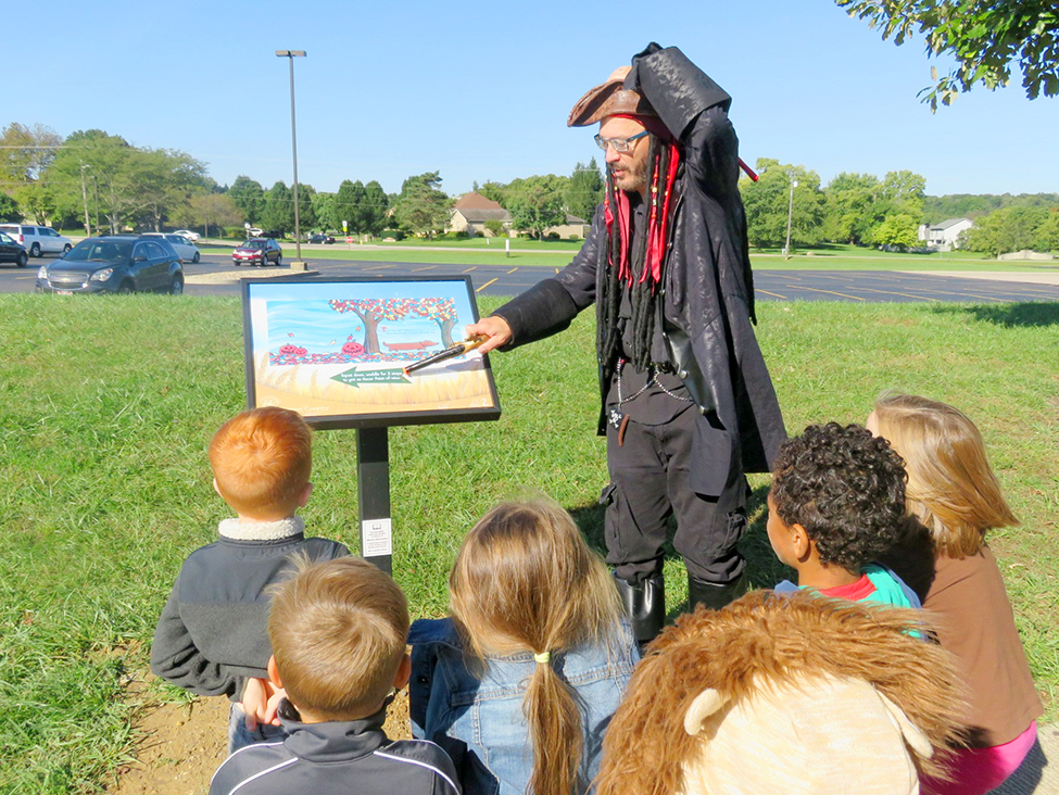 Mr. Tim reads story walk to group of kids