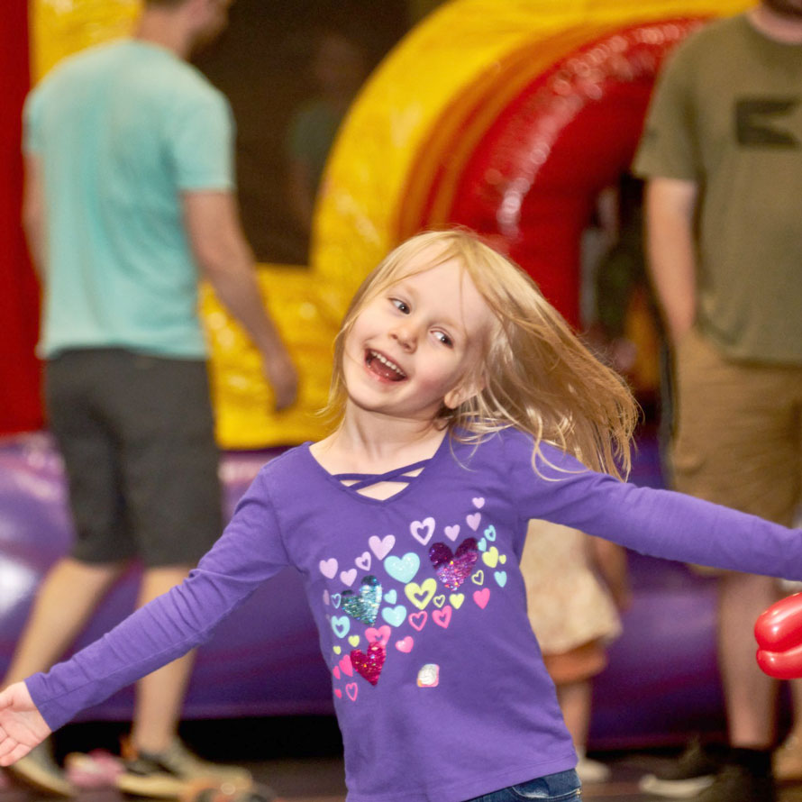 Girl holding arms out wide holding balloon art