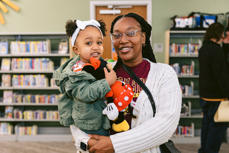 Woman holding young girl. Young girl smiles and holds a Minnie Mouse plushie
